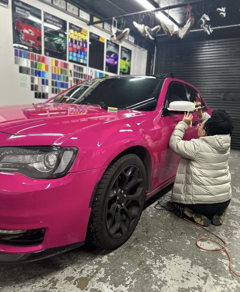 CeCe applying a hot pink wrap to a Chrysler 300 in the C4Wraps shop