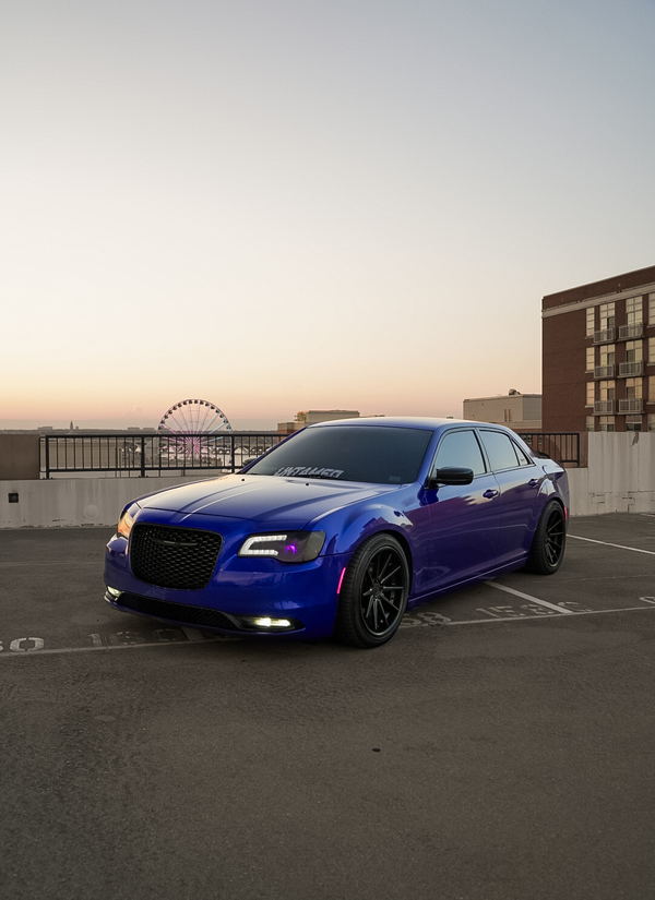 Chrysler 300 in a gloss blue color change wrap at sunset